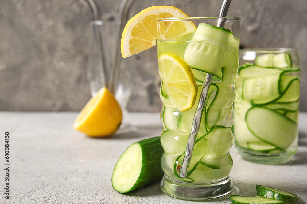 Glasses of infused water with cucumber slices on grey table