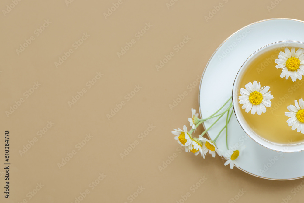 Cup of hot chamomile tea on beige background