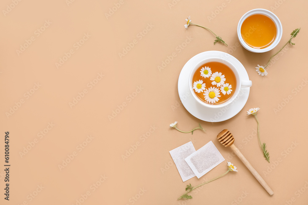 Cup of hot chamomile tea with honey on beige background