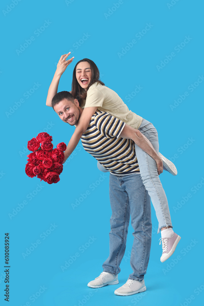 Happy engaged couple with flowers on blue background