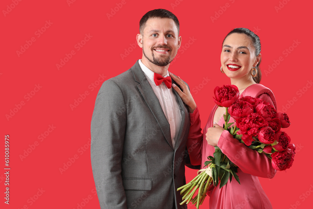 Happy engaged couple with flowers on red background