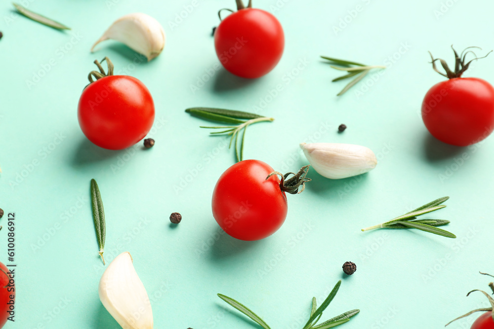 Ripe cherry tomatoes, rosemary, garlic and peppercorn on turquoise background, closeup