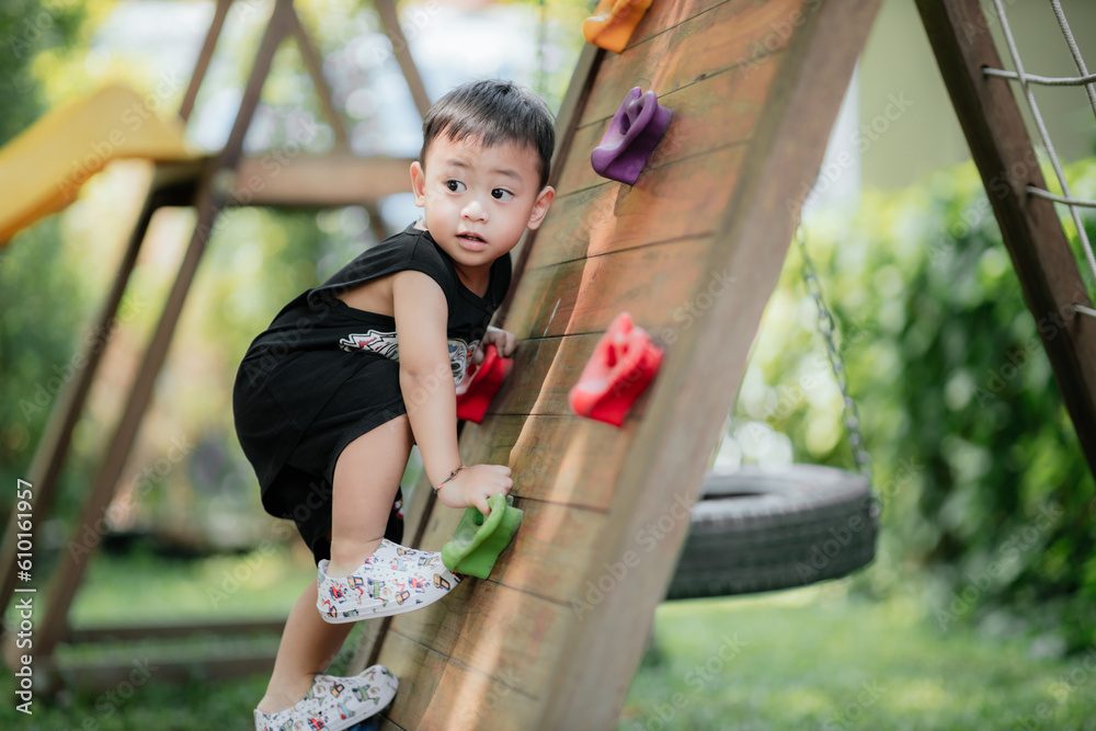 Asian little boy playing in the playground outdoor. Kids play on school or kindergarten yard. Health