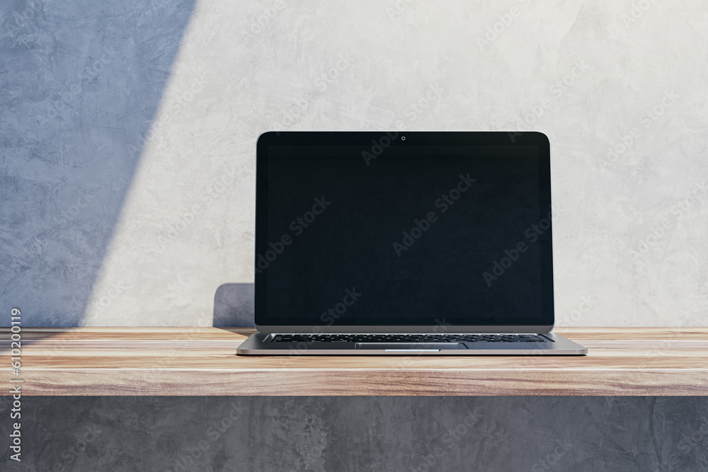 Close up of empty mock up notebook computer screen on wooden desktop and concrete wall background wi