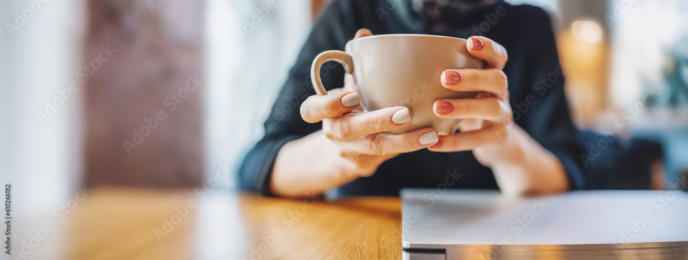 Woman sitting in cafe at the table with. cup of coffee in her hands.