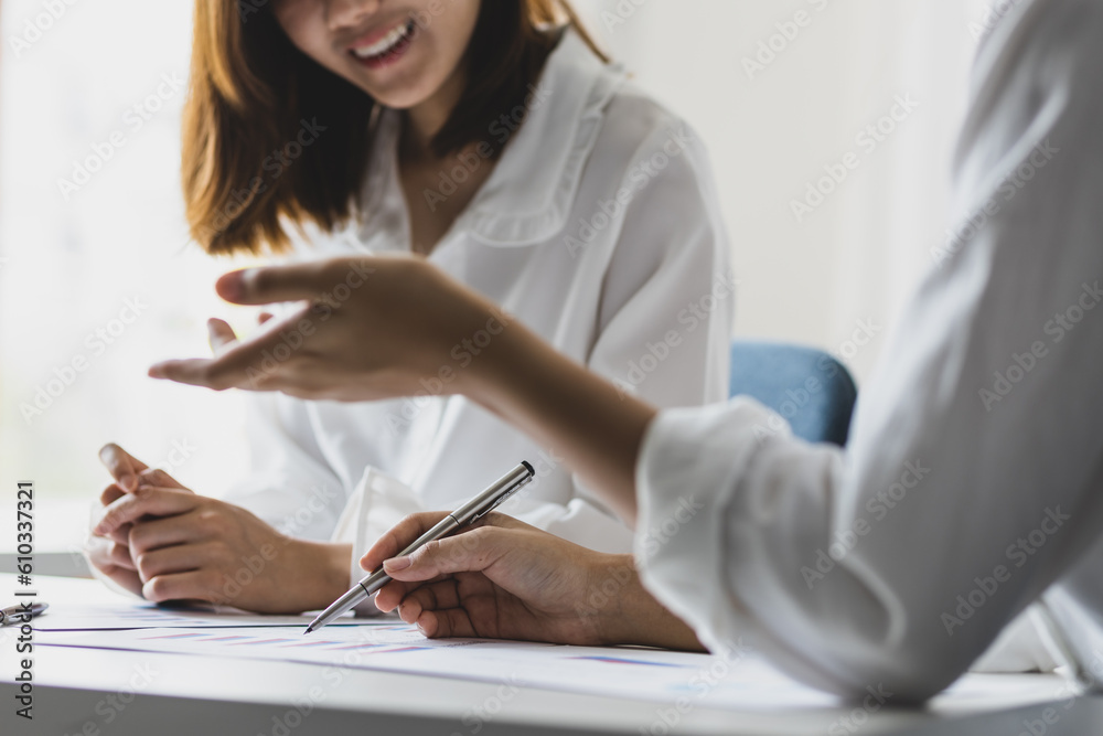 Women collaborating on documents in the office. Colleagues discuss working on a business project.