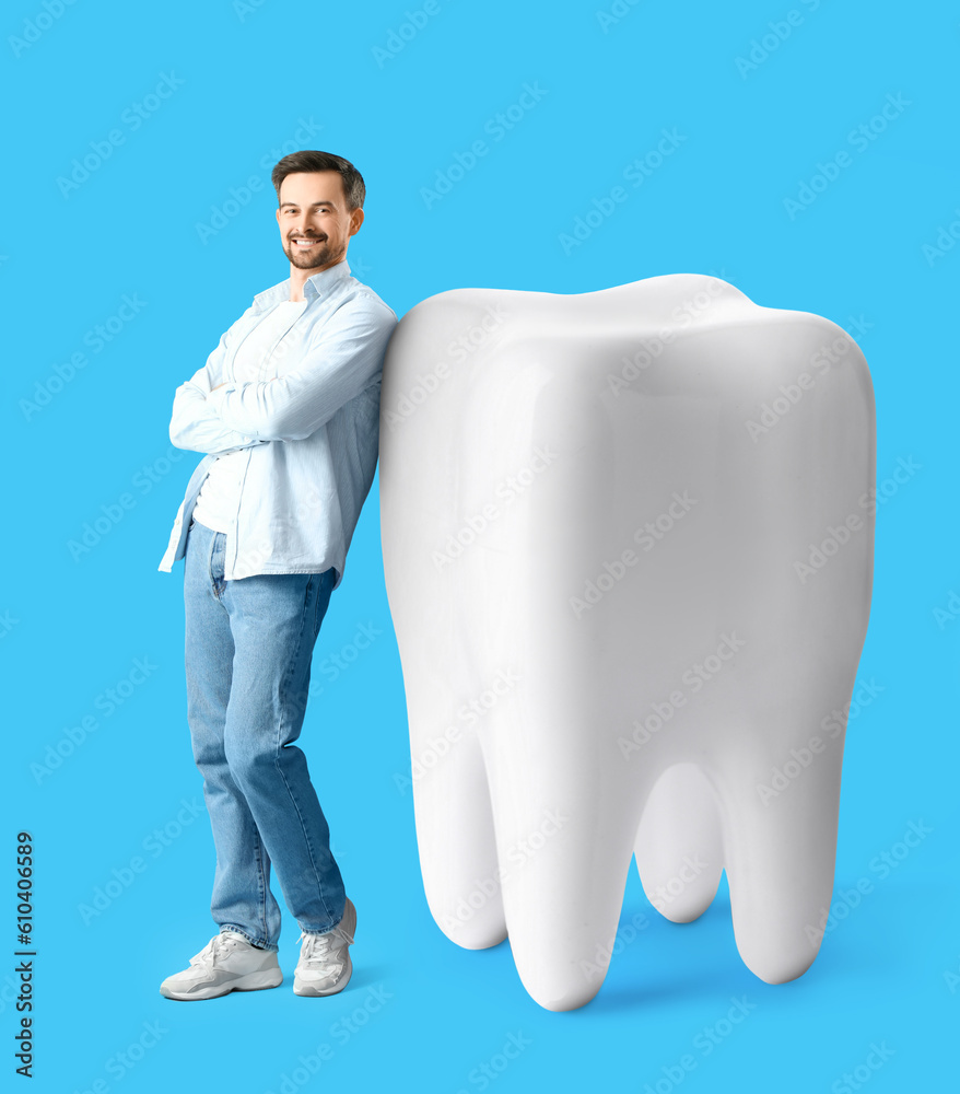 Happy man and big tooth on light blue background