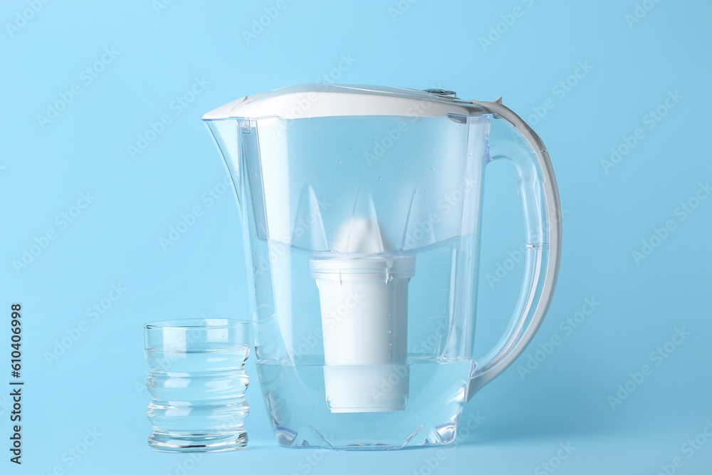 Water filter jug with glass on blue background