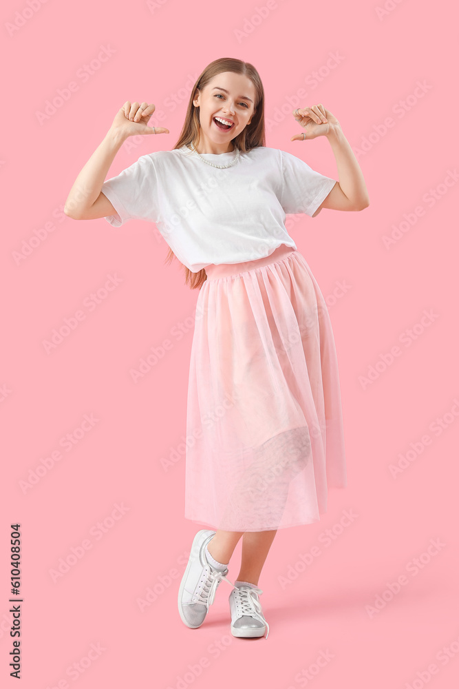 Young woman in t-shirt pointing at herself on pink background