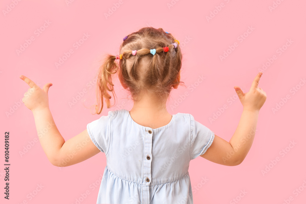 Funny little girl showing loser gesture on pink background, back view