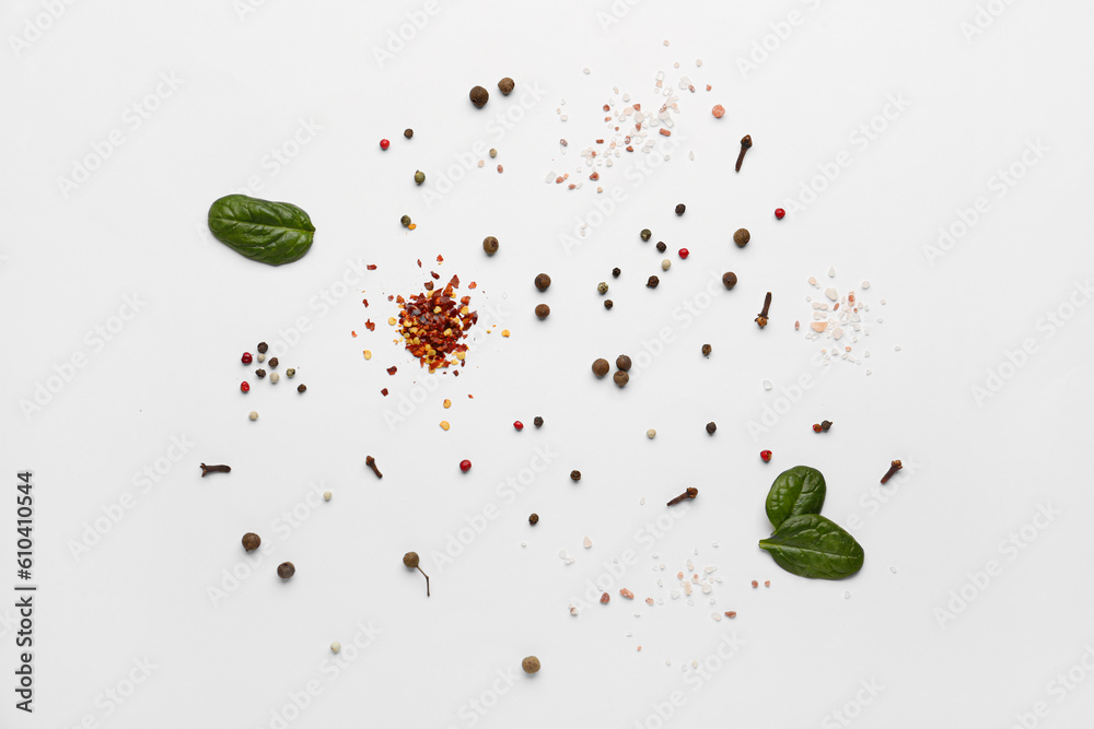 Different spices and spinach leaves on light background