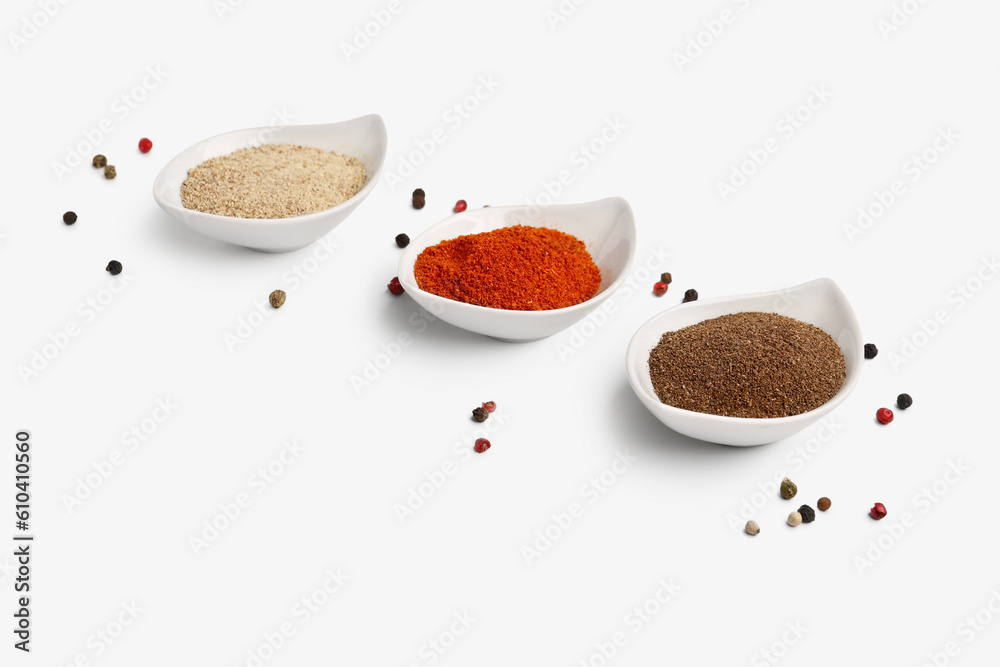 Bowls of spices and peppercorns on light background