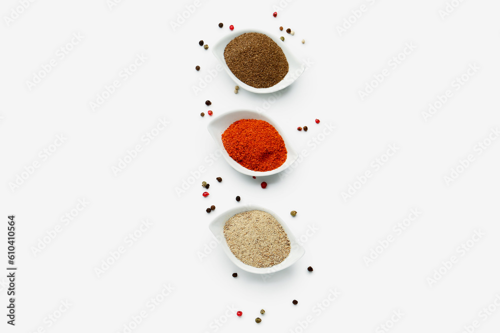 Bowls of spices and peppercorns on light background