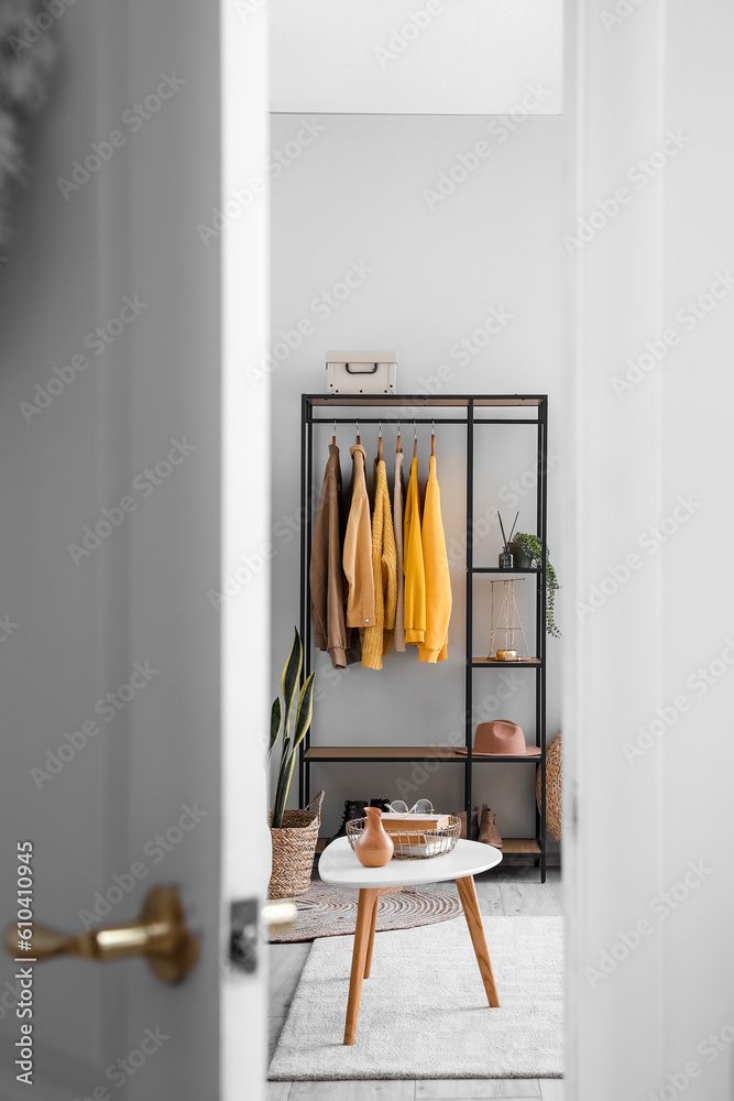 View of living room with shelving unit and clothes through open door