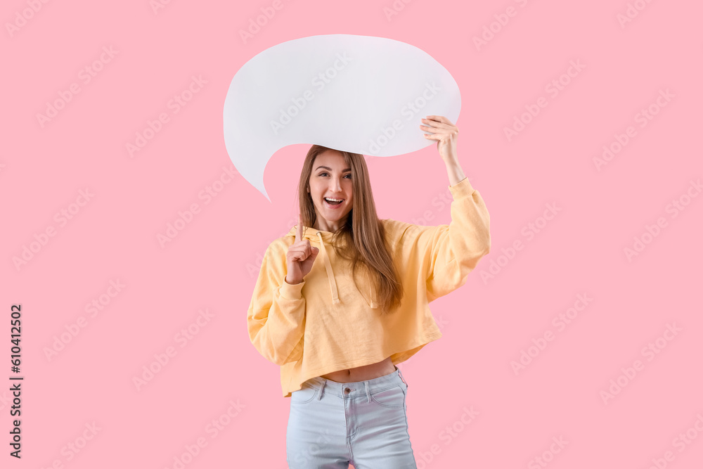 Young woman pointing at blank speech bubble on pink background