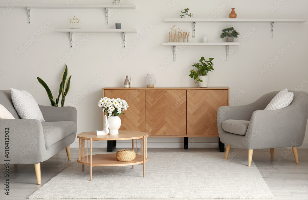 Interior of light living room with grey sofa, armchair and coffee table