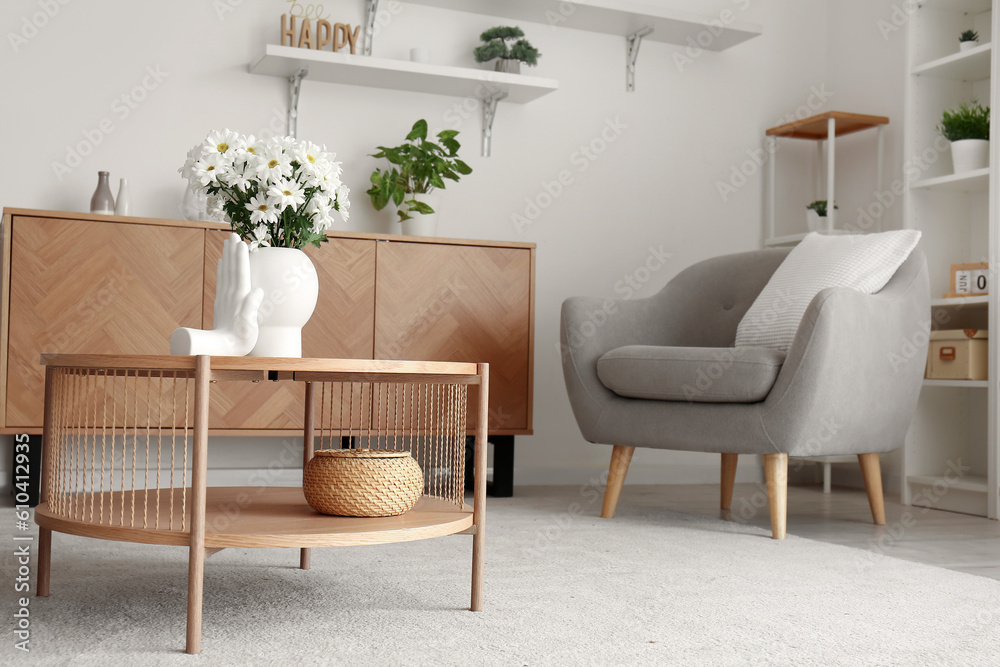 Interior of light living room with grey armchair and coffee table