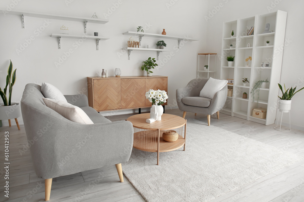 Interior of light living room with grey sofa, armchair and coffee table