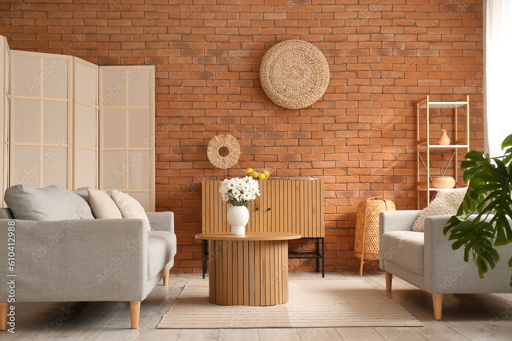 Interior of living room with grey sofas and chrysanthemum flowers on wooden coffee table