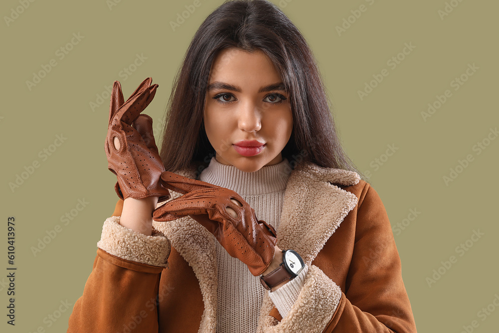 Stylish young woman in leather gloves on green background, closeup