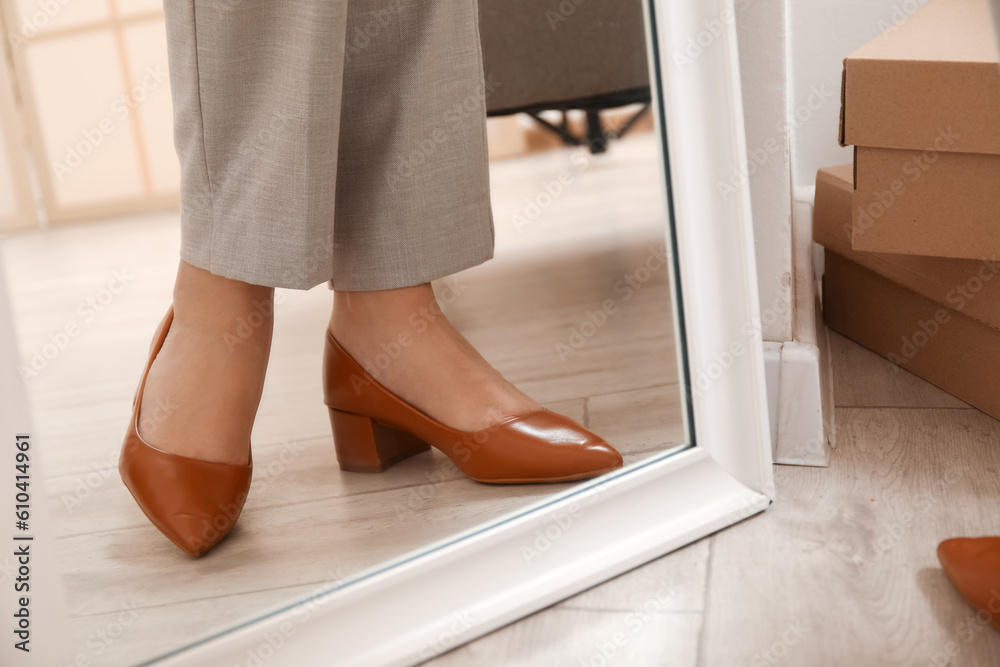 Woman trying on stylish high heeled shoes near mirror, closeup