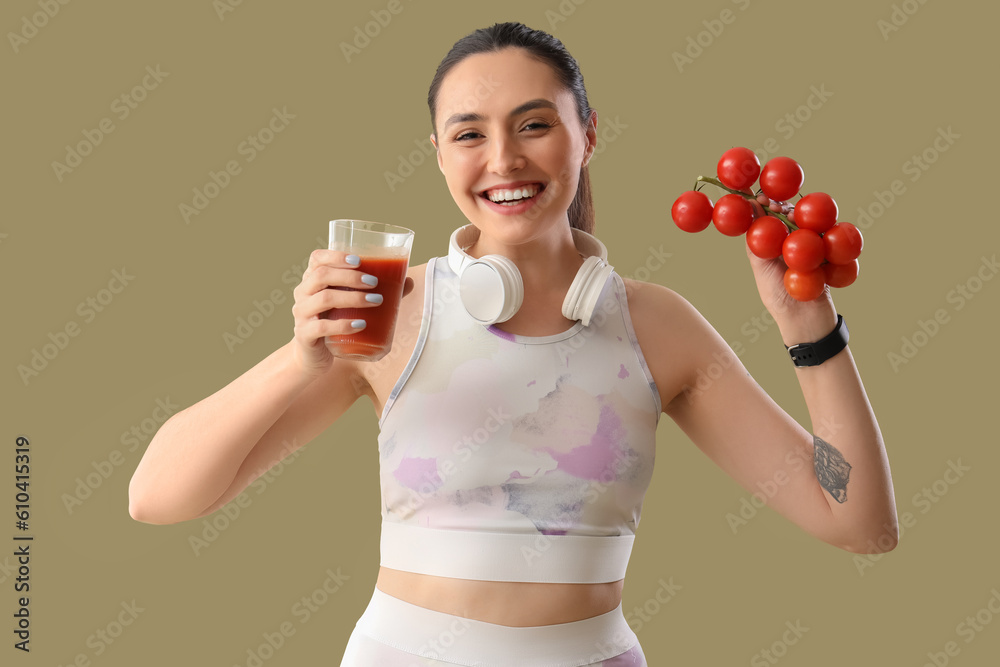 Sporty young woman with glass of vegetable juice and tomatoes on green background