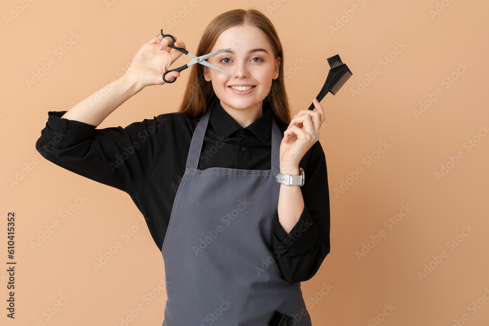 Female hairdresser with scissors and brush on beige background