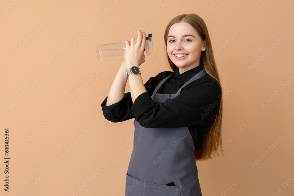 Female hairdresser with spray on beige background