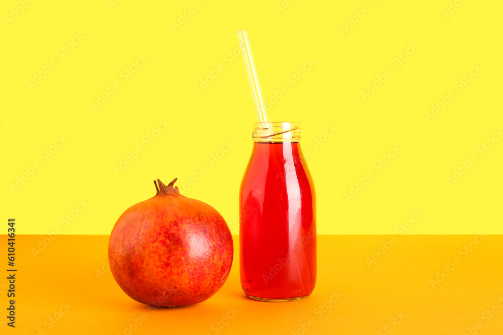 Bottle of fresh pomegranate juice on yellow background