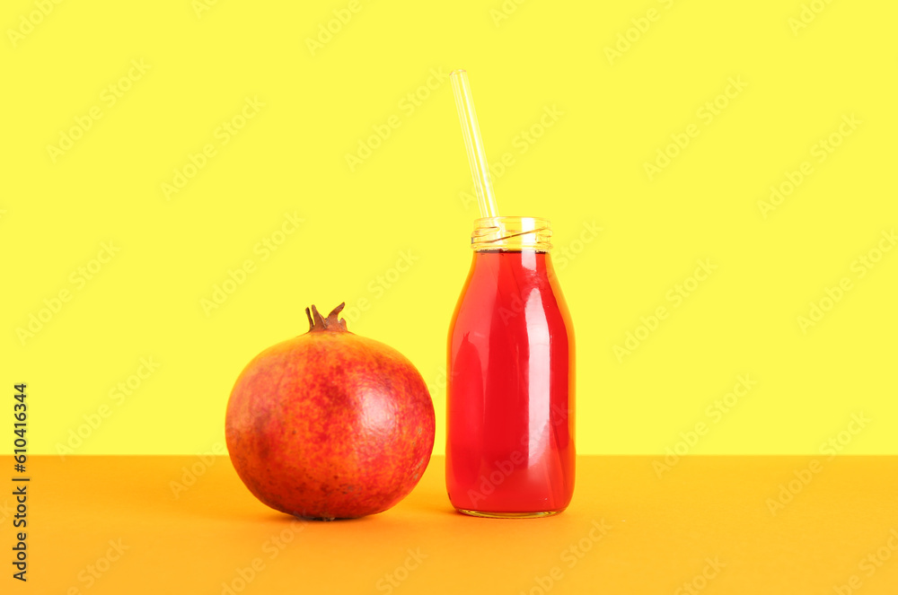 Bottle of fresh pomegranate juice on yellow background