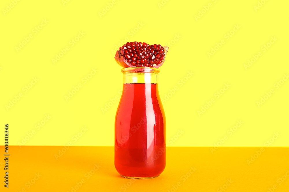 Bottle of fresh pomegranate juice on yellow background