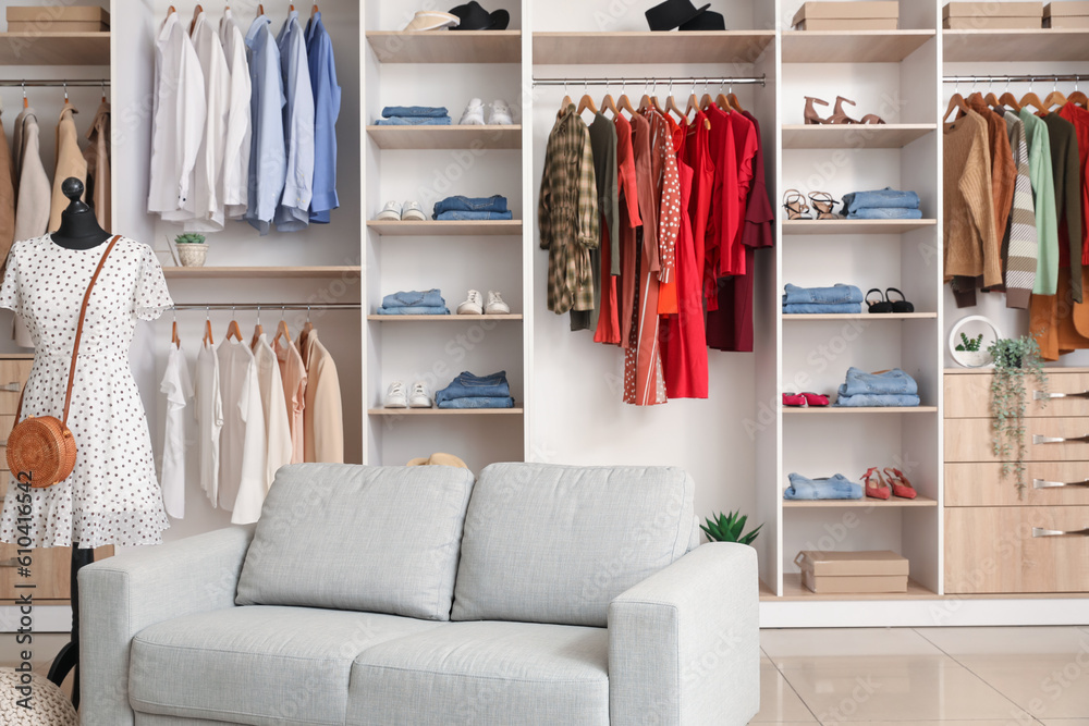 Interior of boutique with stylish clothes, mannequin and sofa