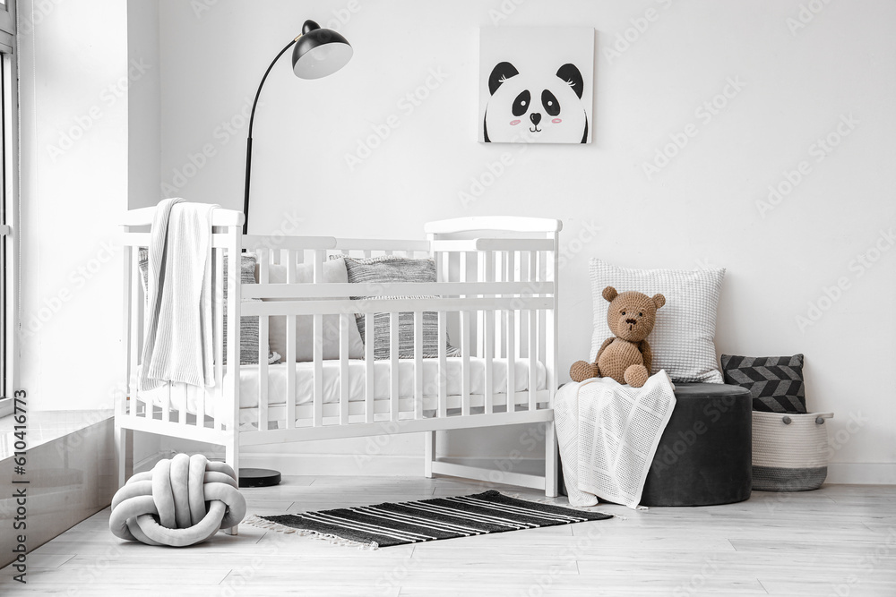 Stylish interior of childrens room  with baby bed and ottoman