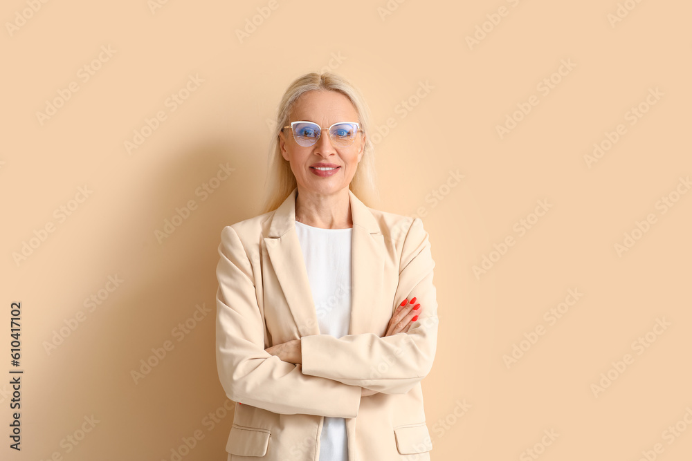 Mature blonde woman in eyeglasses on beige background