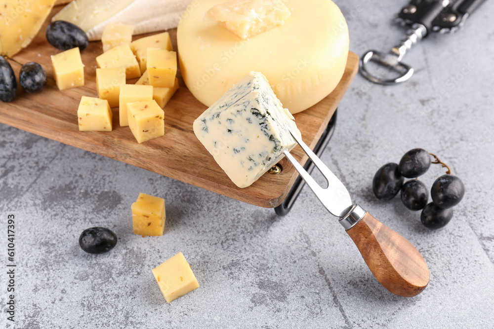 Fork with pieces of tasty cheese on light background