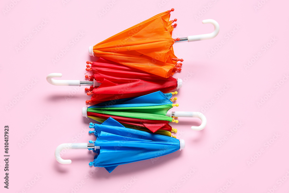 Different mini umbrellas on pink background