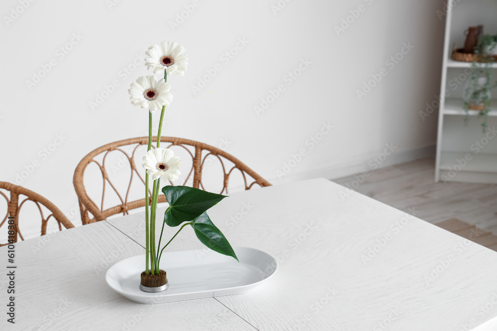 Beautiful ikebana on dining table in room