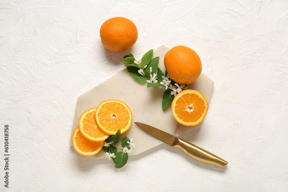 Board of oranges with blooming branches on white background