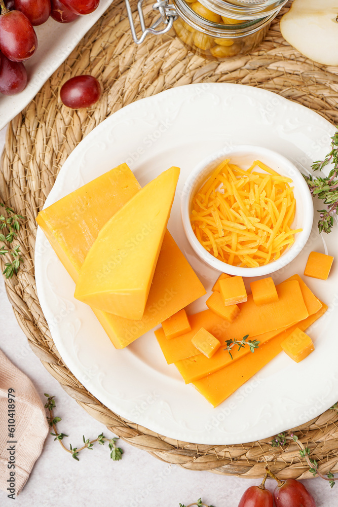 Plate with tasty cheddar cheese, grapes and olives on light background