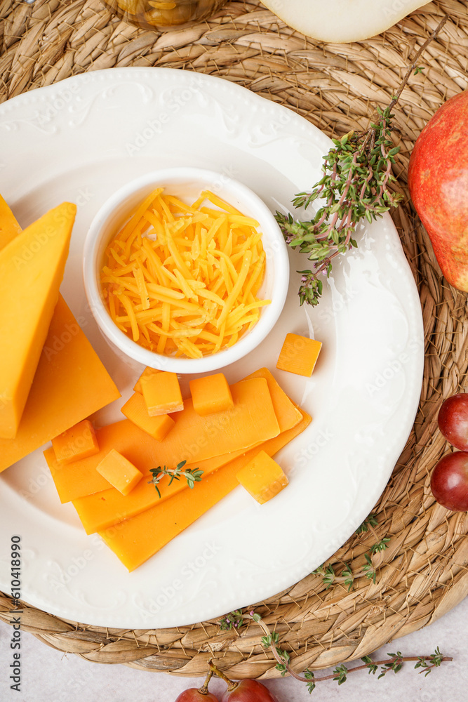 Plate with tasty cheddar cheese, thyme and grapes on light background