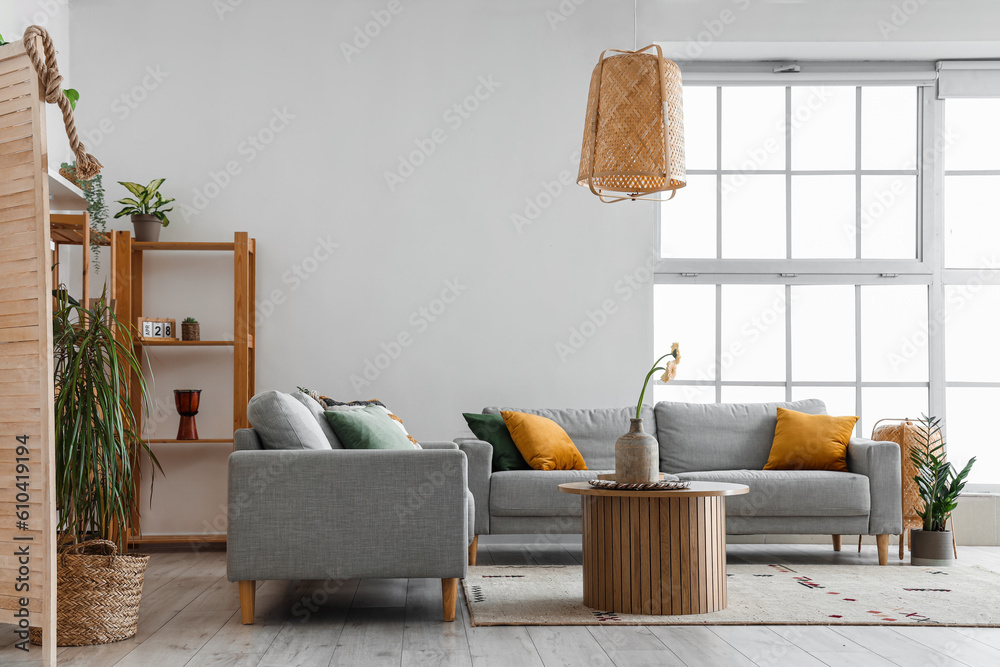 Interior of light living room with grey sofas, wooden coffee table and big window