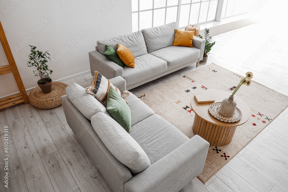 Interior of living room with cozy grey sofas and gerbera flowers on wooden coffee table