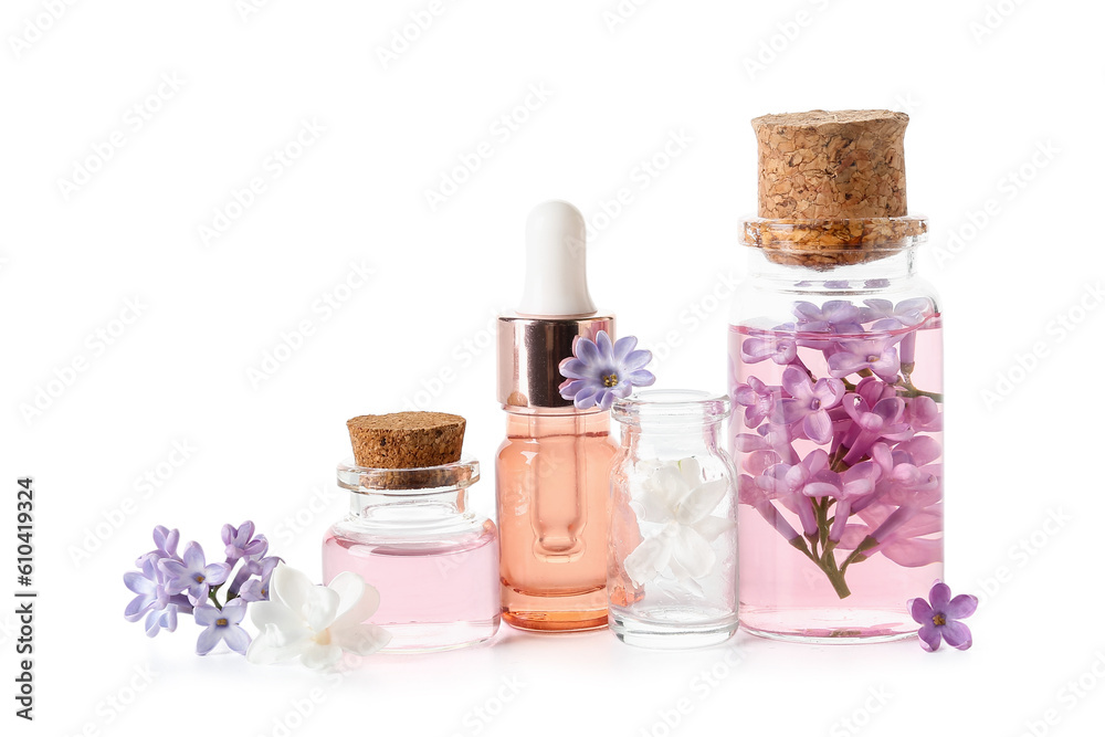 Bottles of cosmetic oil with beautiful lilac flowers on white background