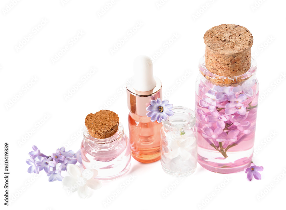 Bottles of cosmetic oil with beautiful lilac flowers on white background