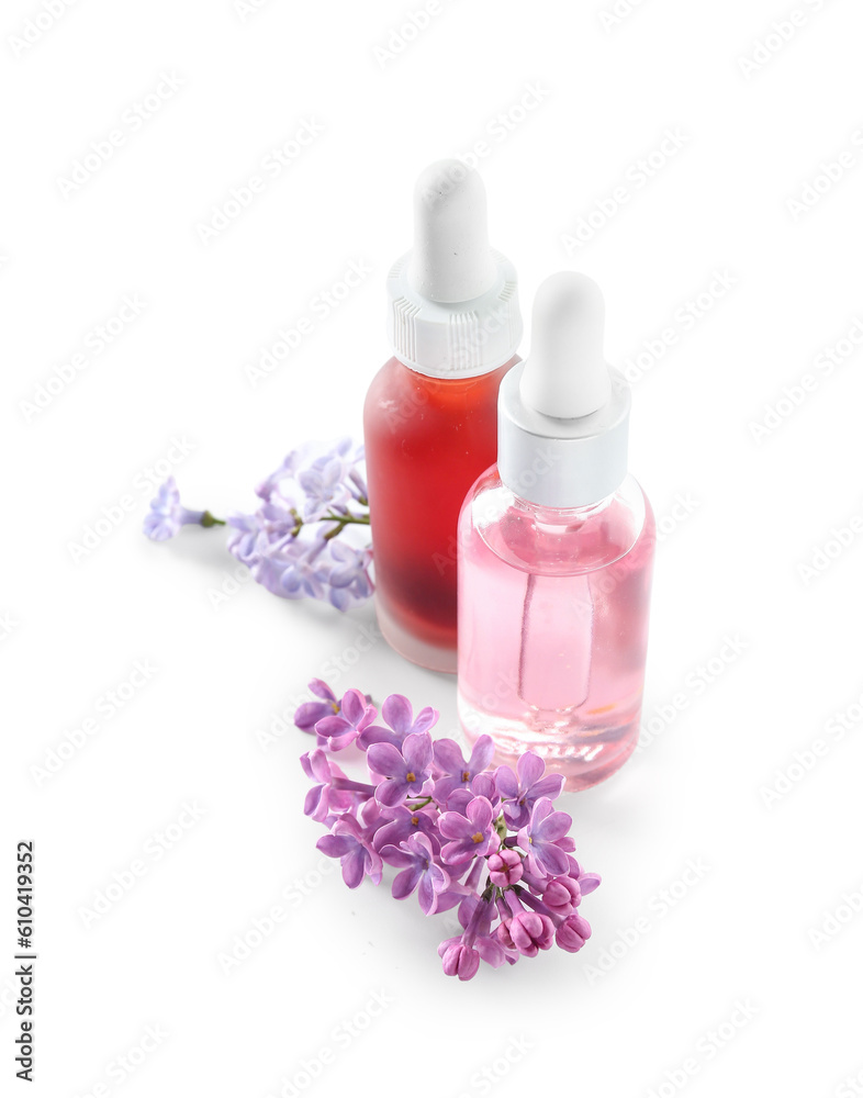 Bottles of cosmetic oil with beautiful lilac flowers on white background