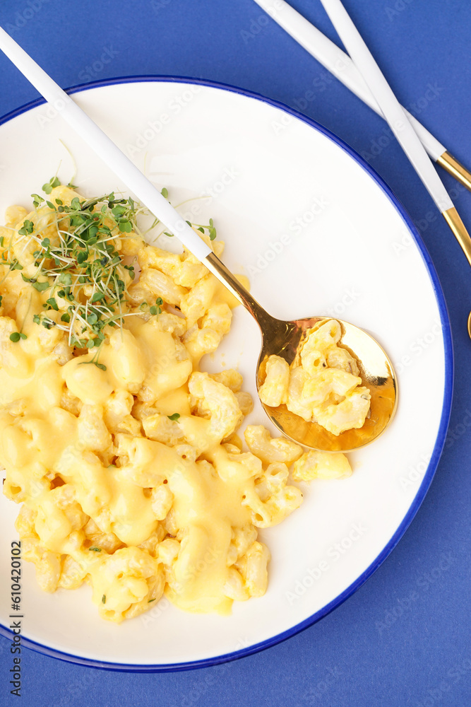 Bowl of tasty Italian pasta with Cheddar cheese on blue background, closeup