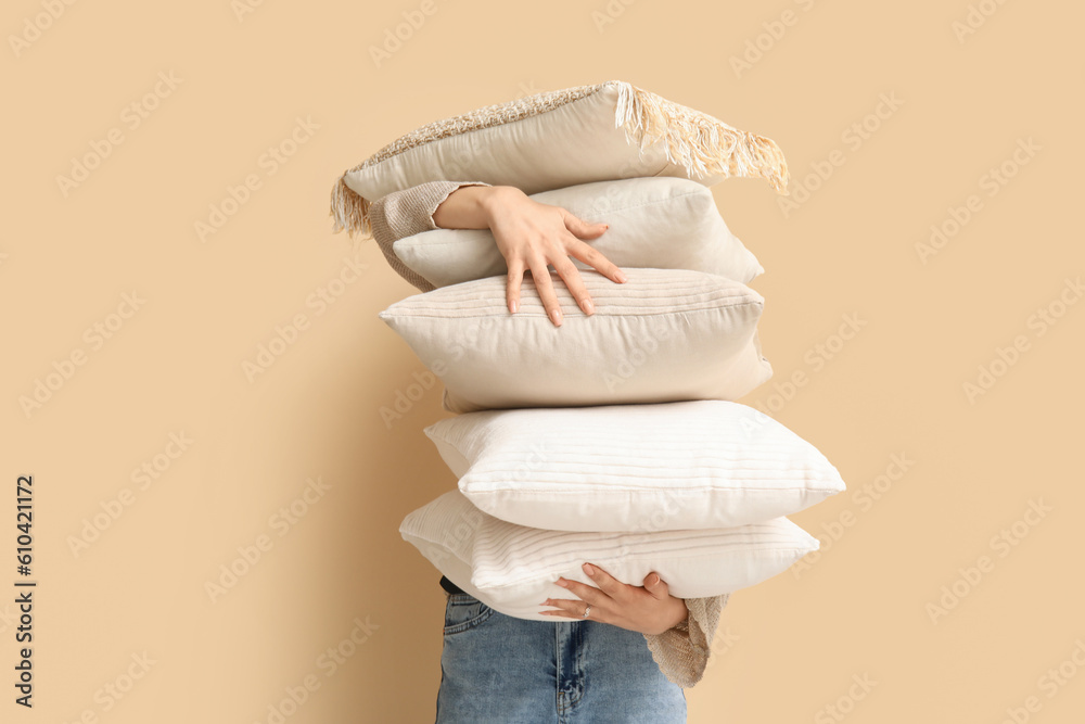 Woman with soft pillows near beige wall