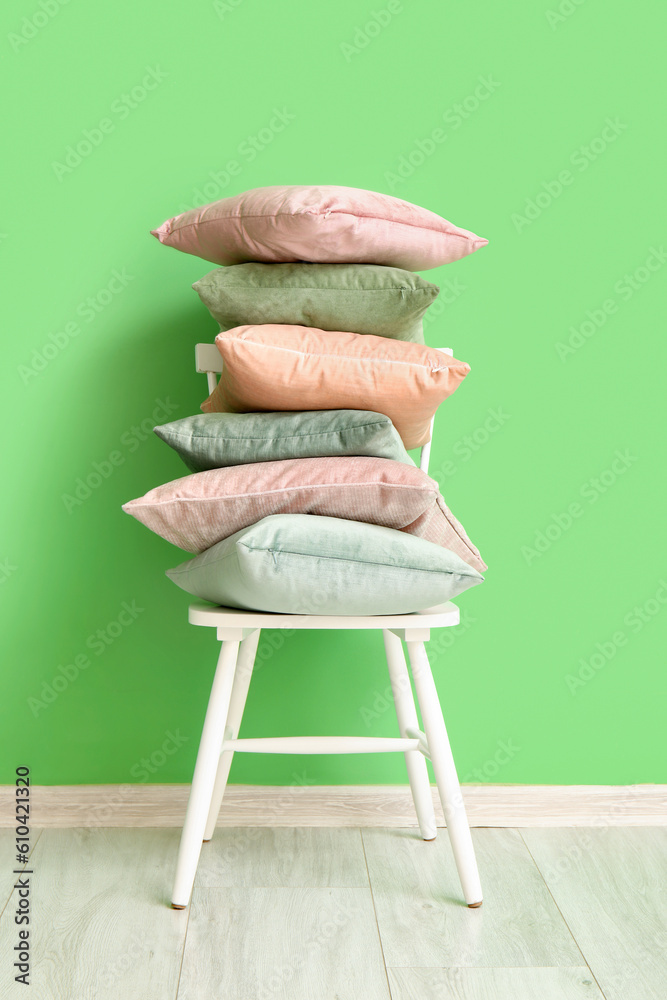 Stylish pillows on chair near green wall