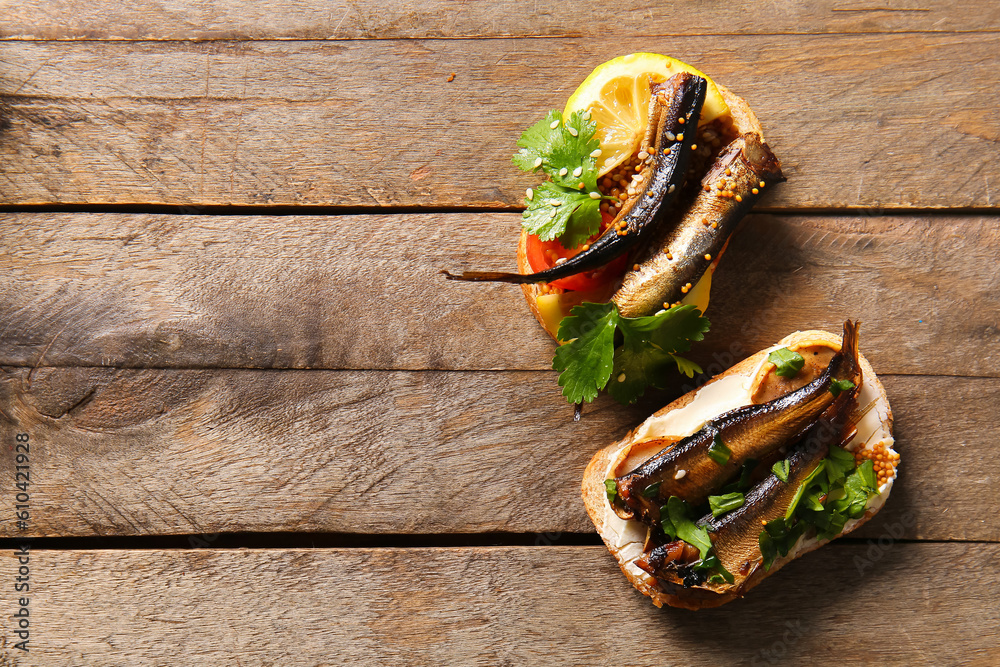 Tasty sandwiches with canned smoked sprats on wooden background