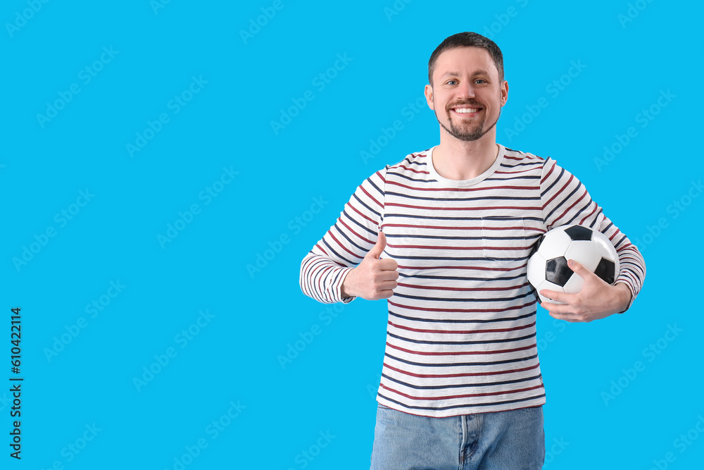 Man with soccer ball showing thumb-up on blue background